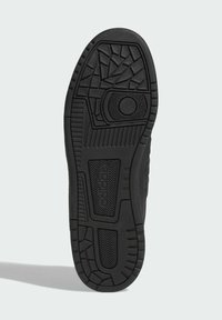 Černá gumová podrážka tenisky s texturovanými vzory, včetně geometrických tvarů a horizontálních drážek, s detailem loga na boku.