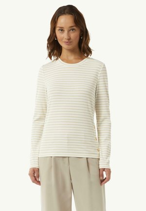 Long-sleeve white top with gold horizontal stripes, round neck, and decorative buttons on the side. Soft, textured fabric.