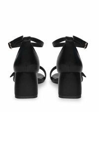 Sorte læder højhælede sandaler med ankelremme og blokhæle. Glat tekstur med et enkelt, strømlinet design og minimalt hardware.