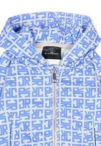 Blauwe zip-up hoodie met een herhalend geometrisch patroon in lichtblauw en donkerblauw. Bevat een frontale ritsluiting en twee zijzakken.