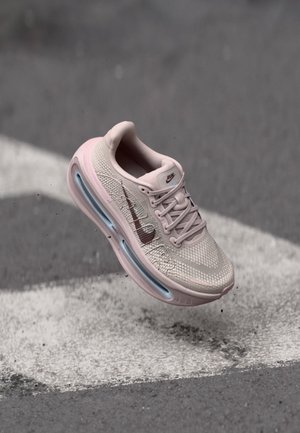 Scarpa da corsa rosa chiaro con tomaia in mesh, accentuata da uno swoosh rosa scuro, dotata di un'unità aria visibile nel tallone e suola texturizzata.