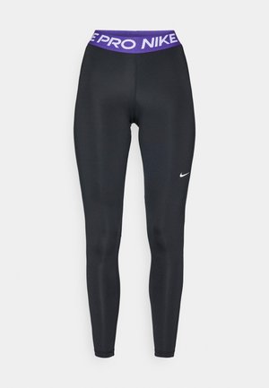 Melnas sporta legingi ar gludu tekstūru, ar purpura jostu, uz kuras ir uzraksts "NIKE PRO" un mazs balts Nike logo vienā pusē.