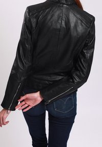 Černá kožená motorkářská bunda s přiléhavým střihem, zipy na manžetách a výraznými švy na ramenou. Hladká textura s minimem detailů.