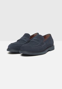 Marineblaue Wildleder-Mokassins mit einem Mokassin-Design, ein glattes Textur, dekorativer Naht und einer robusten Gummisohle.