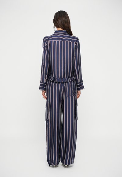 Set di pigiama a righe navy con strisce rosa chiaro; top a maniche lunghe con orlo arricciato e pantaloni larghi con tasche cargo. Morbida texture del tessuto.
