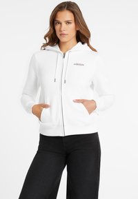 Balta zip-up džemperis su dviem priekinėmis kišenėmis. Su virvute reguliuojamu gobtuvu ir LOGO ant kairiojo krūtinės. Pagamintas iš minkštos medžiagos, su lygiu paviršiumi.