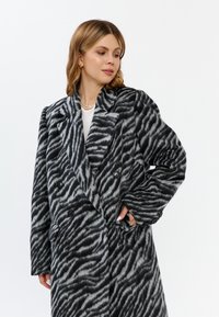 Płaszcz dwurzędowy w czarno-szary wzór zebra, z klapami, teksturowanym materiałem i dwoma przednimi kieszeniami.