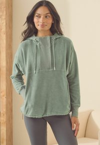 Grøn fleece hættetrøje med en tekstureret brystpanel, snorhætte og ribbede manchetter; designet til komfort med en afslappet pasform.