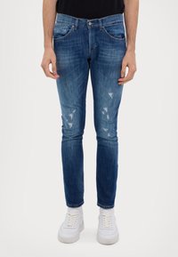 Blå denimjeans med slim fit, med slitna detaljer och en urtvättad effekt, i kombination med vita sneakers.