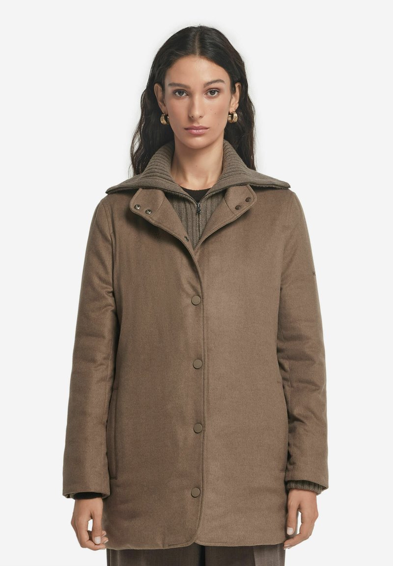 Brun, knäpps kappa med hög krage och ribbad innerskikt. Tillverkad av strukturerad tyg, med sidofickor och tryckknappar.