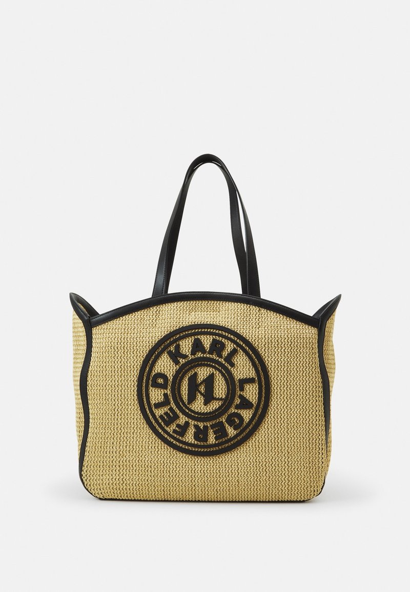 Sac fourre-tout beige tissé avec des bordures et des poignées noires, arborant un logo circulaire Karl Lagerfeld en noir sur le devant.