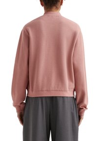 Roze textuur sweatshirt met een ronde kraag, ribbelboorden en een geribde onderrand. Gecombineerd met losse grijze broeken voor een ontspannen pasvorm.