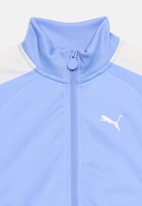 Ανοιχτό μπλε μπουφάν με φερμουάρ, με ριμπ στην όρθια γιακά, λευκά πάνελ στους ώμους και λευκό λογότυπο Puma στο στήθος.