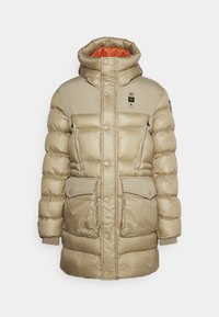 Beżowa pikowana kurtka z wysokim kołnierzem, pomarańczową podszewką, dwoma przednimi kieszeniami, zatrzaskami i pikowaną teksturą.