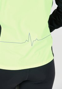 Neon groene technische jas met zwarte accenten, voorzien van een reflecterende hartslaglijn-graphic nabij de zoom, gemaakt van ademend materiaal.