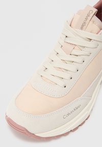 Sneaker beige e rosa chiaro con pannelli in suede e mesh, lacci piatti e suola in gomma con il logo Calvin Klein sul lato.