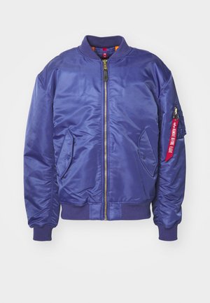 Lilla pommidžakk, valmistatud läikivast kangast, millel on ees tõmblukk, ribikätistega varrukad ja punane kangast silt varrukal.