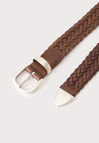 Ceinture en cuir tressé marron avec boucle argentée et embout argenté sur fond clair.