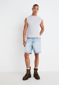 Gray sleeveless textured knit top paired with light blue denim shorts. Brown lace-up combat boots with yellow accents. Simple, casual attire.