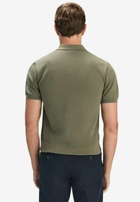 Lyhythihainen, kauluksellinen polo-paita oliivinvihreänä, jossa on teksturoitu kuvio. Ominaisuuksiin kuuluu istuva muotoilu sekä ribbaustetut hihansuut ja kaulus.