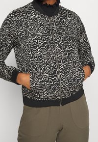 Bomber bunda s černobílým vzorem, se zipem v přední části, žebrovanými manžetami a spodním lemem, s vlnitým designem a uvolněným střihem.