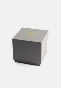 Graue, strukturierte Geschenkbox mit einem goldenenLogoakzent auf dem Deckel und einem soliden Boden. Quadratische Form, robuste Bauweise, geeignet für verschiedene Artikel.