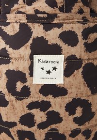 Borsa Kidzroom con un motivo a stampa leopardata marrone e nera, texture del tessuto con cuciture visibili e un'etichetta bianca con il logo del marchio.
