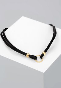 Sort ruskind choker halskæde med guldfarvede metal detaljer og en central ring, med to snoretråde bundet i hver ende.