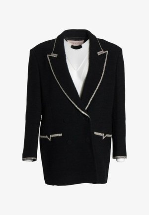 Blazer nero doppiopetto con rifiniture argento su rever, tasche e polsini sopra un top bianco, con etichetta Valentino all’interno del colletto.