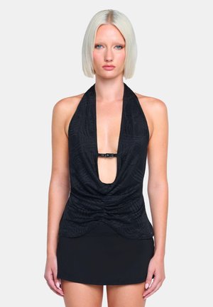 Schwarzes Haltertop mit tiefem V-Ausschnitt, Raffung an der Taille und einem Metallverschluss am Ausschnitt, kombiniert mit einem schwarzen, figurbetonten Rock.