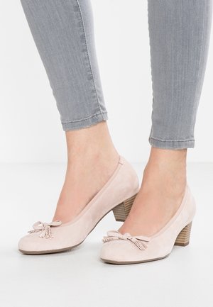 Talons en suède rose pâle avec un bout rond, un petit nœud et un détail clouté ; dotés d'un talon en bois empilé et d'une texture lisse.