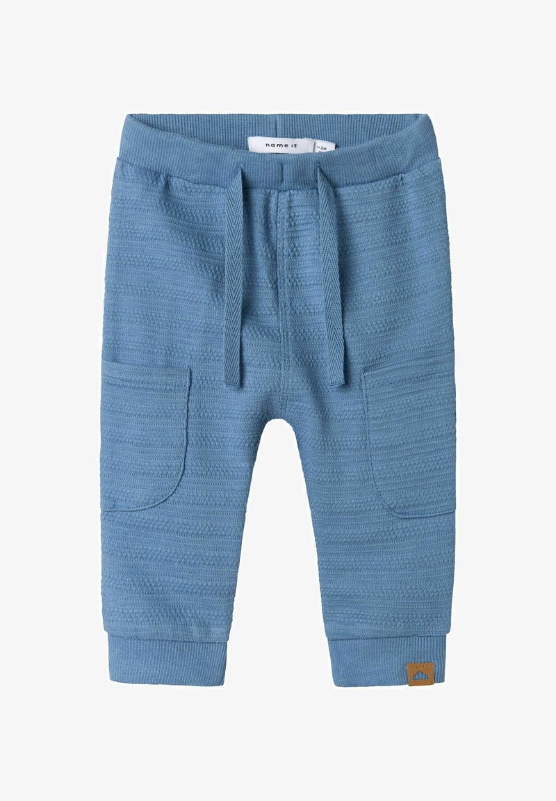 Pantaloni per bambini in maglia blu con un motivo testurizzato, vita elastica, cordoncino e tasche laterali. Presenta un'etichetta marrone con il marchio.