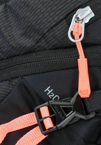 Schwarzer Rucksackstoff mit hexagonalem Muster, ausgestattet mit oranger Reißverschlusslasche, schwarzem Schnallenverschluss und geprägtem "H2O"-Detail.