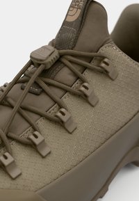 Jasnobrązowe sneakersy z wytrzymałą cholewką o diamentowym wzorze, elastycznymi sznurowadłami i gumową podeszwą zapewniającą przyczepność.