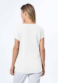 T-shirt bianco a maniche corte con scollatura rotonda e vestibilità rilassata, caratterizzato da una leggera trama e dettagli con orlo curvo.