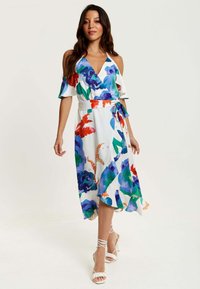 Floral wrap dress in white featuring colorful patterns in blue, green, and red, with cold-shoulder sleeves and a tied waist detail.