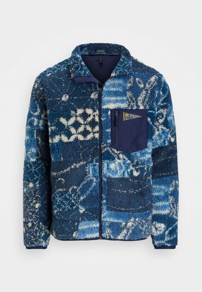 Minkštas džemperis mėlynos spalvos atspalviuose su tekstūriniu raštu. Džemperis turi užtrauktuką priekyje ir krūtinės kišenę su kontrastinga tamsiai mėlyna klape.