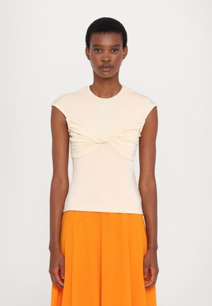 Cream short-sleeved top with twisted design at the front, paired with a bright orange pleated skirt. Smooth texture and fitted silhouette.