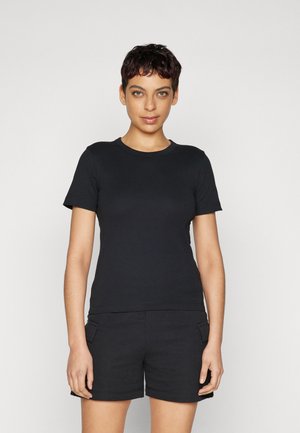 Svart t-skjorte med korte ermer og rund hals, laget av glatt stoff. Sammen med svarte shorts med sidelommer.