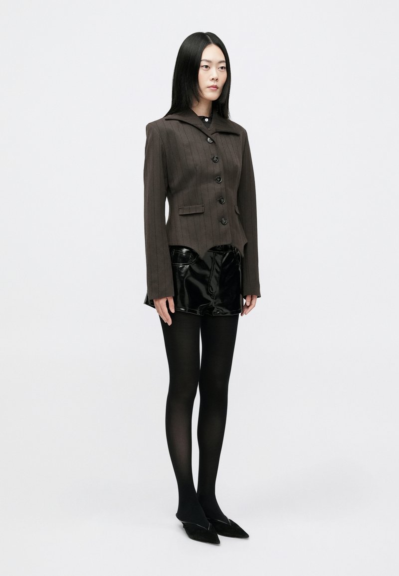 To-delt outfit med en brun stribede blazer med seks knapper, parret med glinsende sorte shorts og sorte tights. Glat tekstur, moderne pasform.