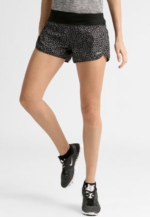 Shorts de sport noirs avec un motif texturé, dotés d'une large ceinture noire. Associés à des chaussures de course noires et blanches.