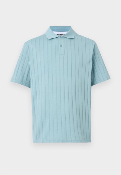 Ανοιχτό μπλε κοντομάνικο πόλο με κάθετη ριμπ υφή και λαιμόκοψη με δύο κουμπιά σε λευκό φόντο.