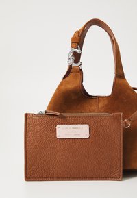Brown leather handbag with a suede texture and a detachable zippered wallet, featuring a silver hardware detail and a brand label.