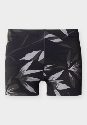 Sorte badebukser med et gråt og hvidt tropisk bladmønster, fladt lagt ud på en lys baggrund.