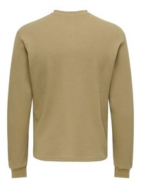 Chemise à manches longues en kaki, fabriquée en tissu gaufré texturé. Elle présente un col ras du cou et des poignets côtelés. Design simple et sans ornement.