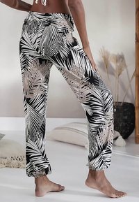 Zwarte en crèmekleurige lichte broek met een palmbladpatroon, elastische tailleband en gerimpelde boorden. Soepele textuur, comfortabele pasvorm.