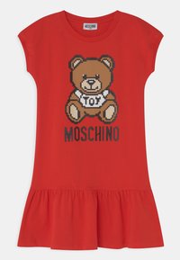 Robe en coton rouge avec un ourlet volanté, présentant un graphique de teddy bear pixelisé et le texte "MOSCHINO" en noir sous l'ours.