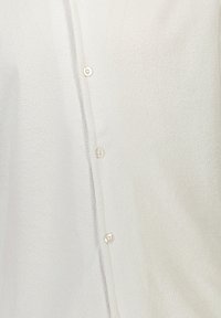 Witte button-up shirt vervaardigd van gestructureerde stof, met een voorkraag met ronde, lichte knopen en een iets relaxte pasvorm.
