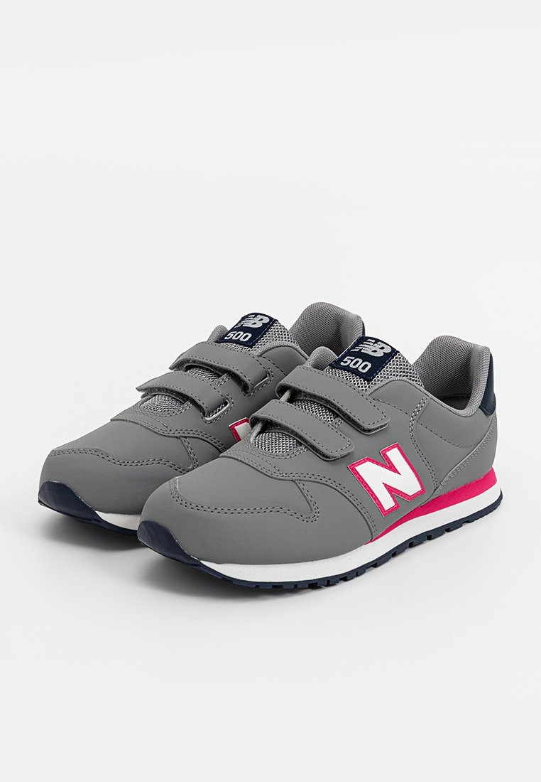 Zapatillas deportivas grises con correas de velcro, paneles de malla, acentos en blanco y rosa, forma redondeada y suelas de goma para tracción.