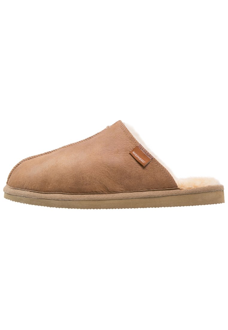 Brown suede slipper with a fur lining, slip-on design, rounded toe, and a textured rubber sole. Brand tag visible on the upper side.
